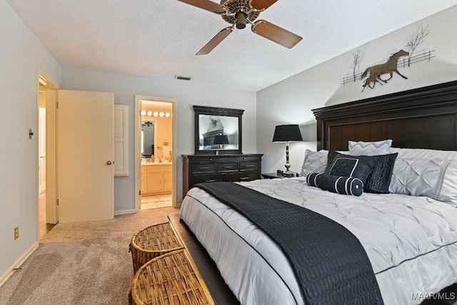 bedroom with visible vents, a ceiling fan, light colored carpet, ensuite bath, and a textured ceiling