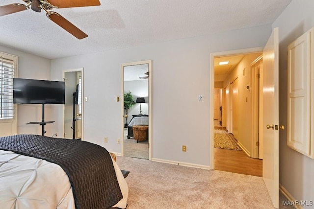 bedroom with light carpet, a textured ceiling, a ceiling fan, and baseboards