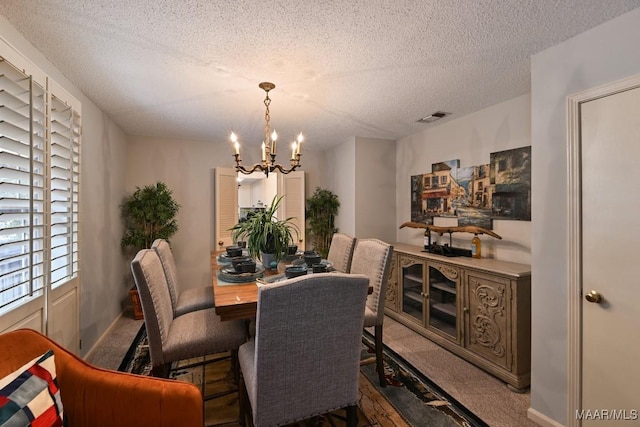 carpeted dining room with an inviting chandelier, visible vents, and a textured ceiling