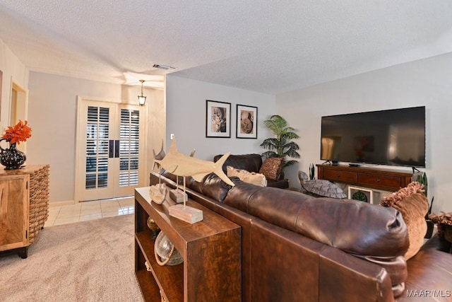 living area with light tile patterned floors, a textured ceiling, light colored carpet, visible vents, and french doors