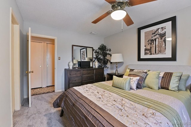 bedroom with light carpet, ceiling fan, visible vents, and a textured ceiling