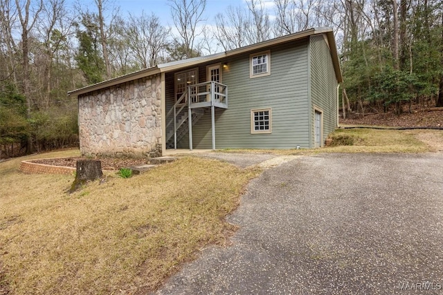 view of front of property featuring aphalt driveway, stone siding, and a garage