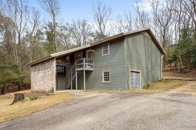 view of front facade featuring driveway, stone siding, and stairs