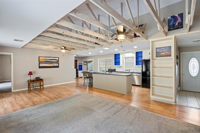 kitchen with a center island, dark countertops, visible vents, stainless steel dishwasher, and freestanding refrigerator