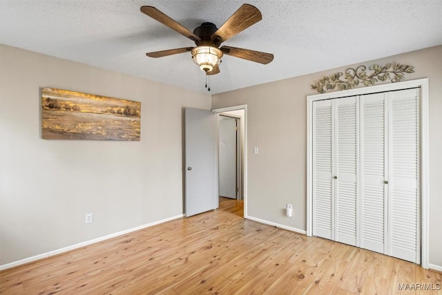 unfurnished bedroom featuring light wood-type flooring, a closet, a textured ceiling, and baseboards