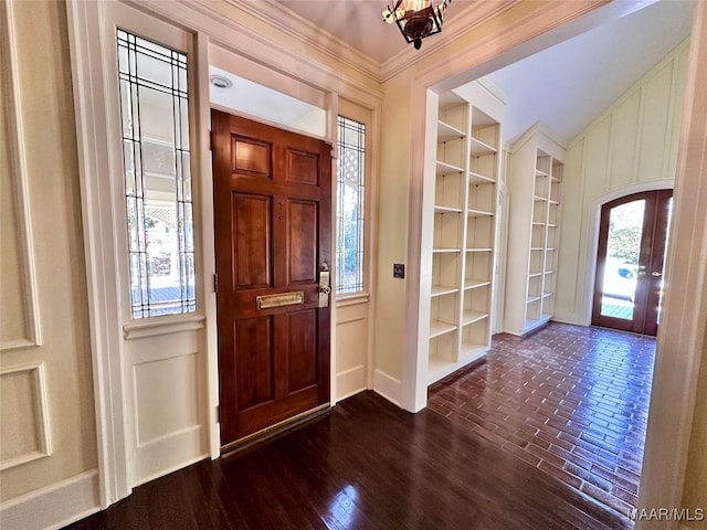 foyer entrance with arched walkways, a decorative wall, dark wood-style flooring, french doors, and ornamental molding