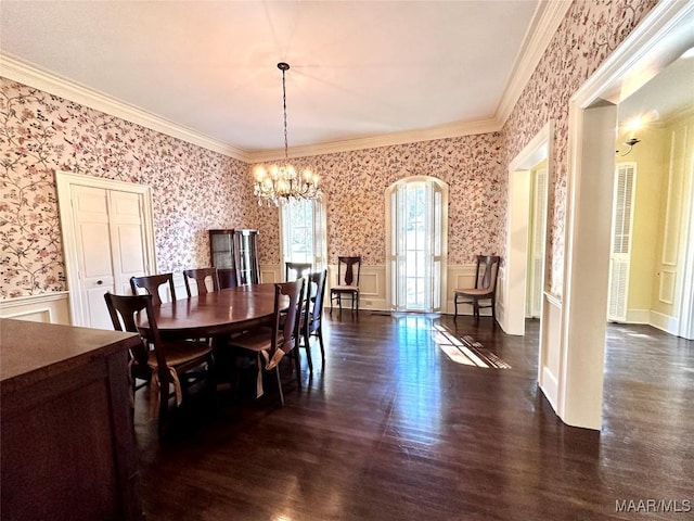 dining area with wallpapered walls, dark wood finished floors, wainscoting, an inviting chandelier, and crown molding