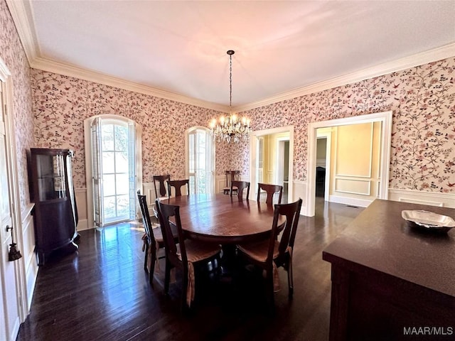 dining space with a chandelier, ornamental molding, wainscoting, dark wood finished floors, and wallpapered walls