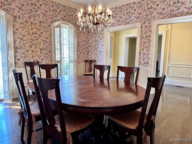 dining area featuring wood finished floors, visible vents, ornamental molding, wainscoting, and wallpapered walls