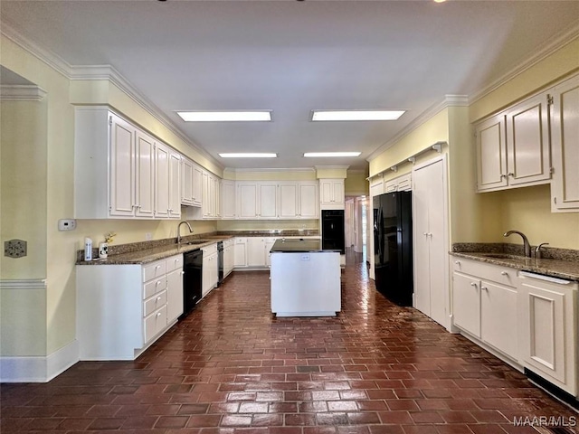 kitchen featuring dark stone countertops, crown molding, a sink, and black appliances