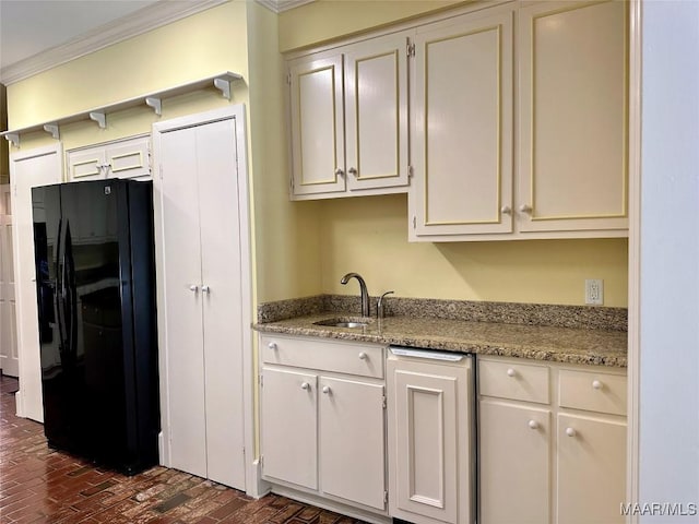 kitchen with ornamental molding, light stone countertops, brick floor, black fridge, and a sink