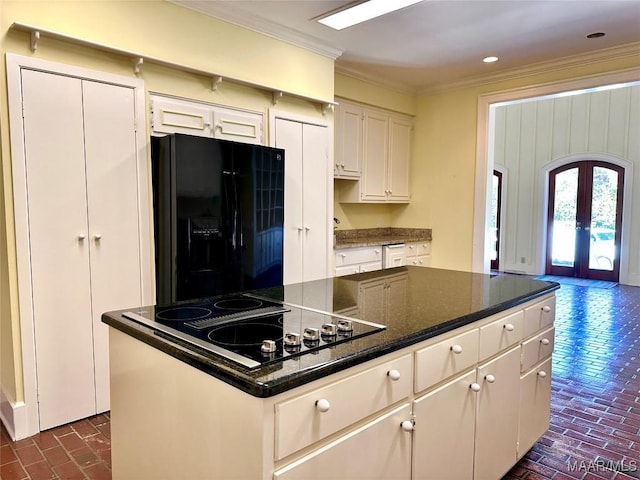 kitchen with white cabinets, a kitchen island, brick floor, crown molding, and black appliances