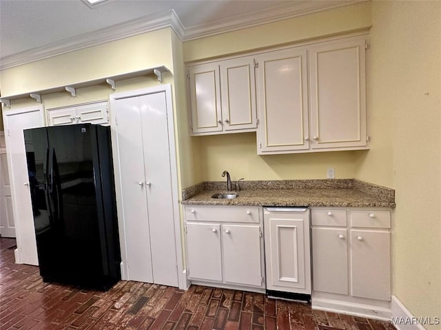 kitchen with white cabinets, ornamental molding, light stone countertops, black fridge, and a sink