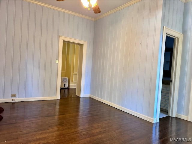 spare room with dark wood-style floors, baseboards, ornamental molding, and a ceiling fan