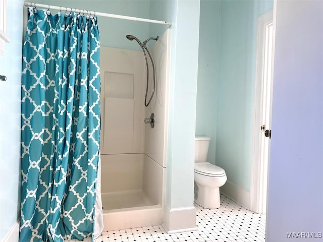 bathroom featuring toilet, a shower stall, and tile patterned floors