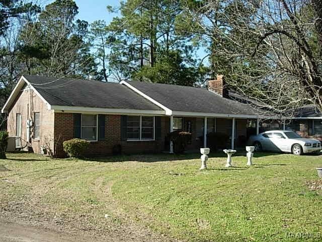 ranch-style house featuring a carport, brick siding, a chimney, and a front lawn