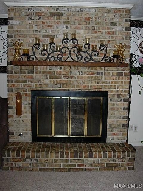 interior details with a brick fireplace, carpet, and ornamental molding