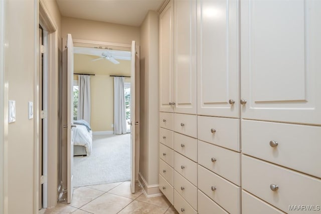 hall featuring light carpet, baseboards, and light tile patterned floors