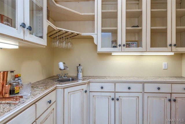 kitchen with light countertops, a sink, glass insert cabinets, and white cabinets