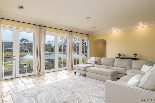 living area with a water view, arched walkways, stone tile flooring, and ornamental molding