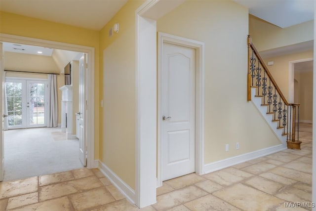 corridor with stairway, baseboards, stone tile flooring, and french doors