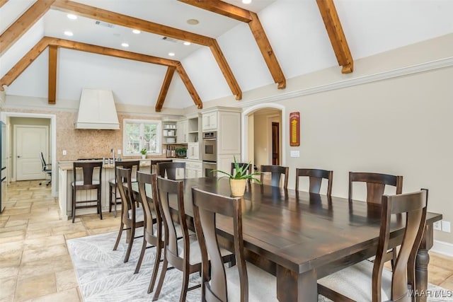 dining space with baseboards, visible vents, arched walkways, vaulted ceiling with beams, and stone tile flooring