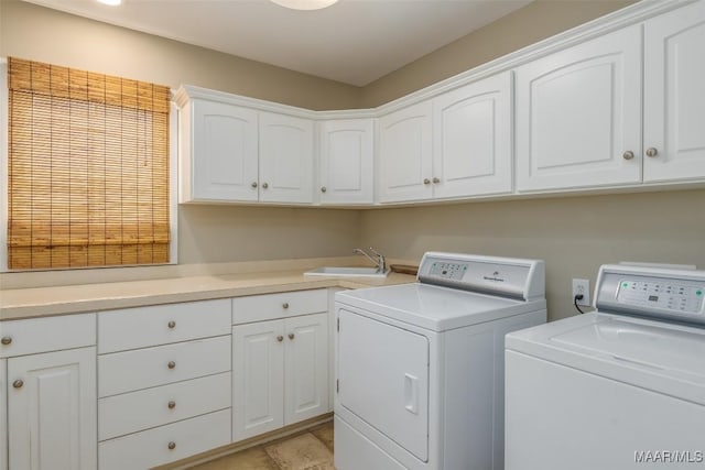 laundry room with washing machine and dryer, cabinet space, and a sink