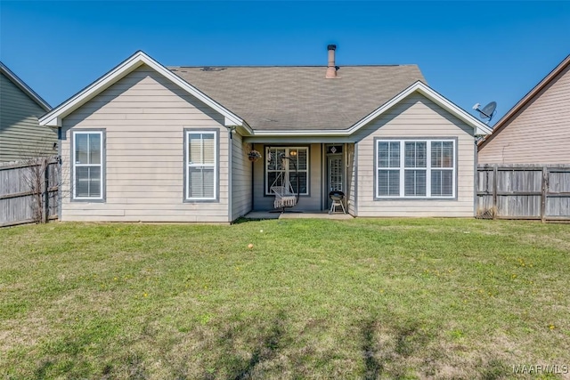 rear view of property with fence and a lawn
