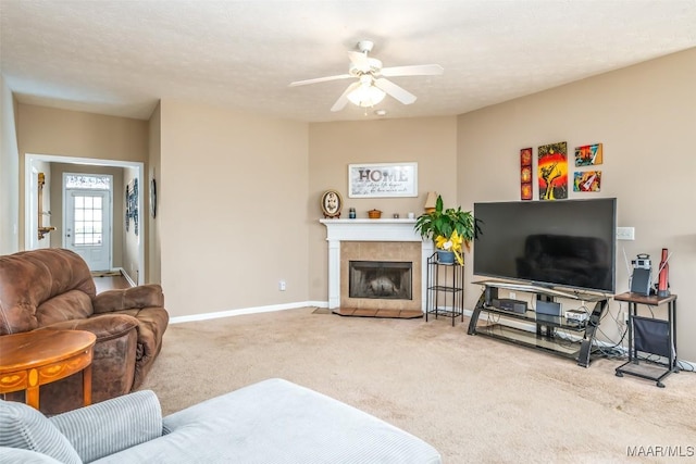 living area featuring baseboards, a tiled fireplace, ceiling fan, a textured ceiling, and carpet floors