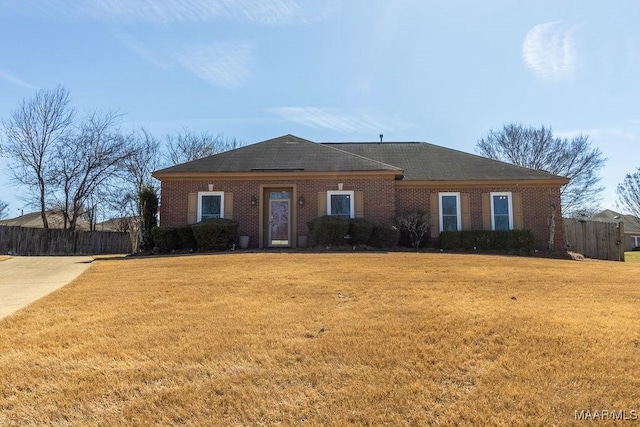 single story home featuring brick siding, fence, and a front yard