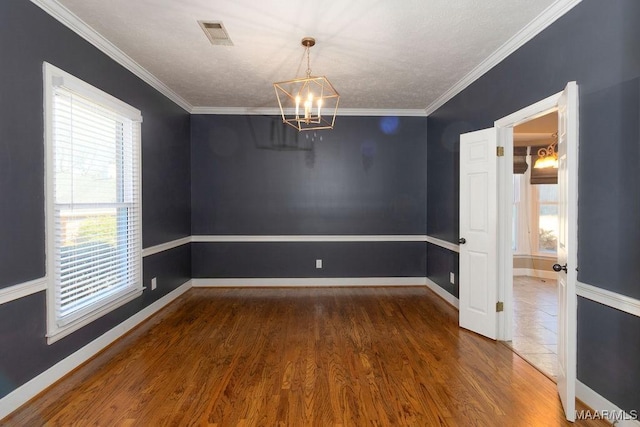 unfurnished room with baseboards, crown molding, an inviting chandelier, and wood finished floors