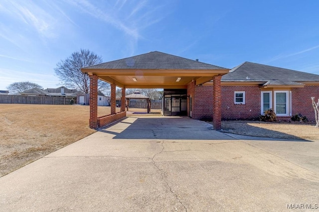 exterior space with concrete driveway, an attached carport, an outdoor structure, and fence