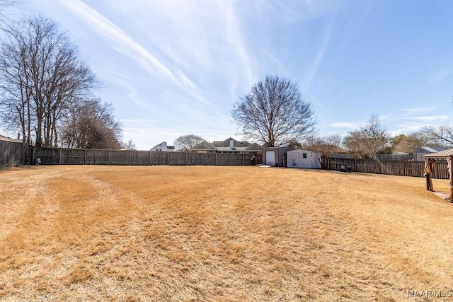 view of yard with a fenced backyard, an outdoor structure, and a storage shed