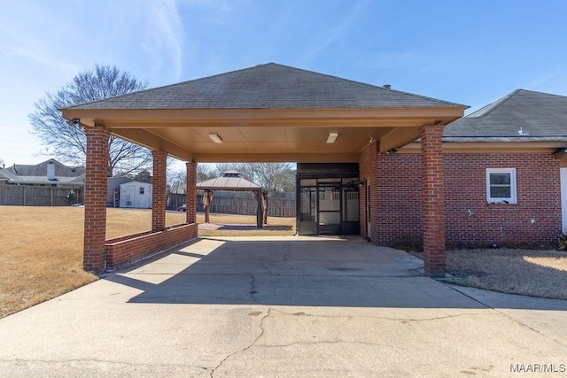 view of patio / terrace featuring concrete driveway, a gazebo, a storage shed, fence, and an outdoor structure