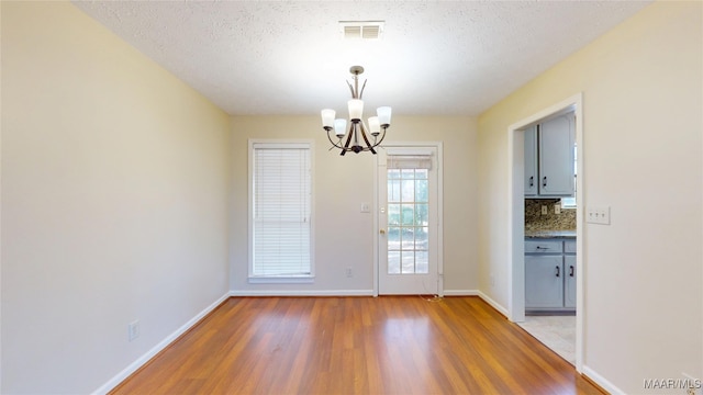 entryway with visible vents, a textured ceiling, light wood-style flooring, and baseboards