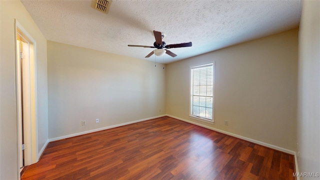 spare room featuring a ceiling fan, baseboards, visible vents, and dark wood-style flooring