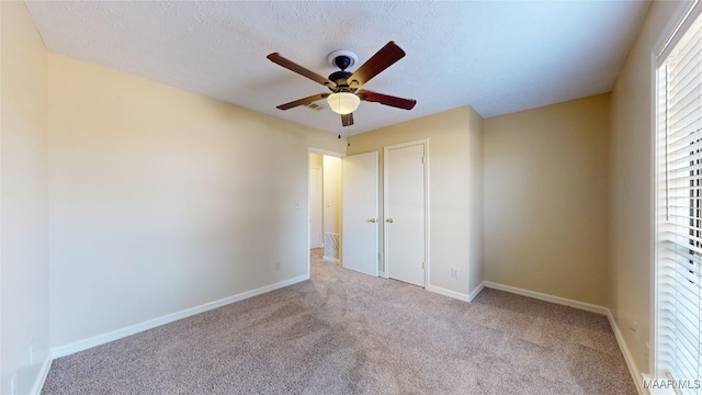 unfurnished bedroom featuring a textured ceiling, light colored carpet, and baseboards