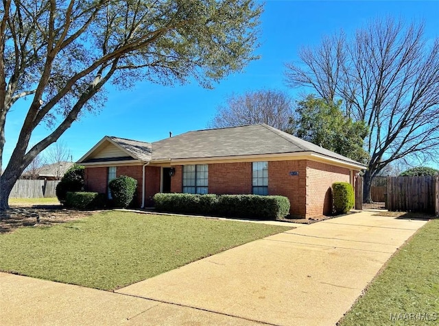 single story home with driveway, a front yard, fence, and brick siding