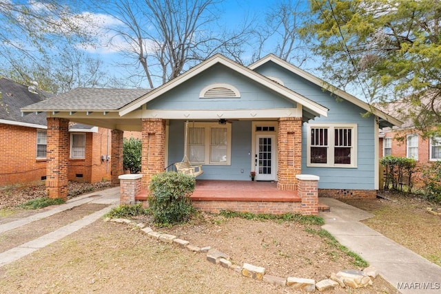 bungalow-style house featuring covered porch, brick siding, crawl space, and a shingled roof