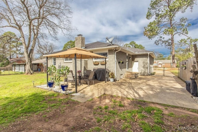 rear view of property featuring a lawn, a patio, fence, a gazebo, and brick siding