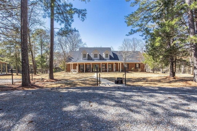 new england style home featuring covered porch and brick siding