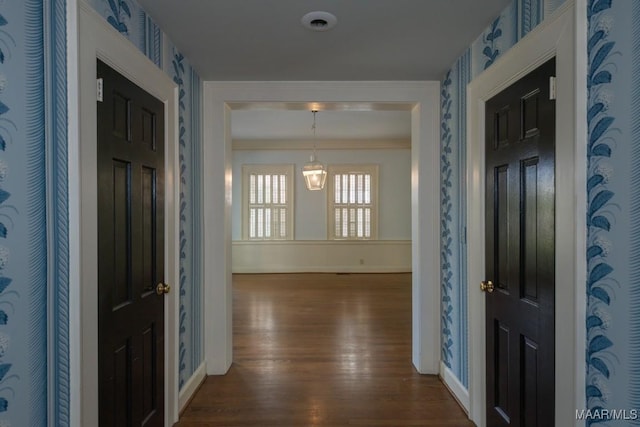 entryway featuring dark wood-style floors, crown molding, baseboards, and wallpapered walls
