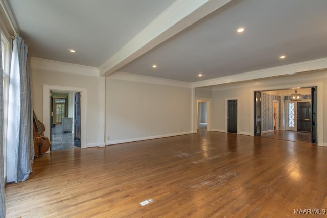 empty room with a healthy amount of sunlight, ornamental molding, and wood finished floors