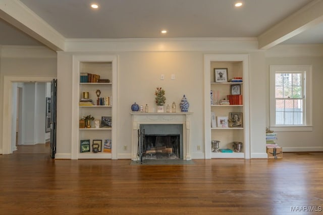 unfurnished living room featuring built in shelves, dark wood-type flooring, crown molding, and a fireplace with flush hearth
