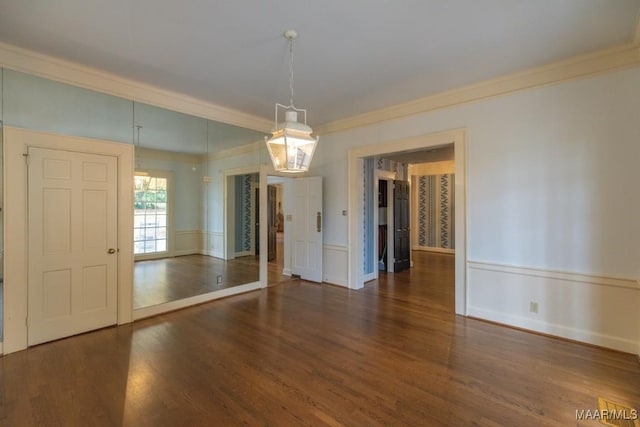 unfurnished dining area featuring a wainscoted wall, dark wood-type flooring, and crown molding