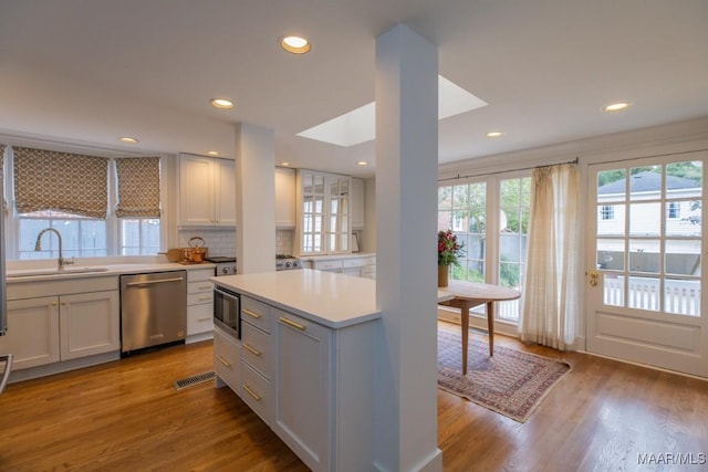 kitchen with a sink, stainless steel appliances, light countertops, and light wood-style flooring