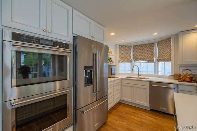 kitchen featuring stainless steel appliances, a sink, light countertops, and white cabinets