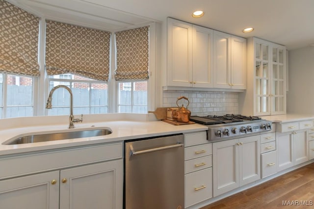 kitchen with stainless steel appliances, light countertops, a sink, and white cabinetry