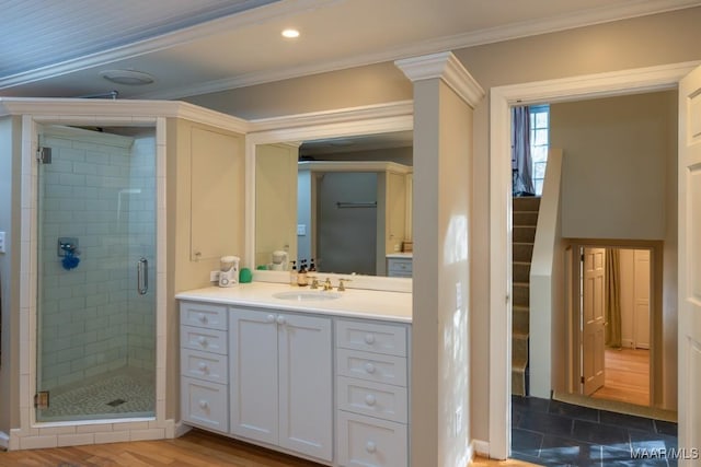 bathroom featuring ornamental molding, a stall shower, wood finished floors, and vanity