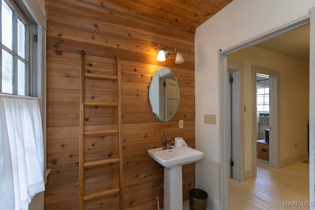 bathroom with wood walls, a sink, and wood finished floors